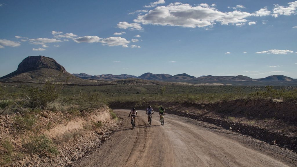 Riders in Cochise County with peaks rising in the distance behind them.